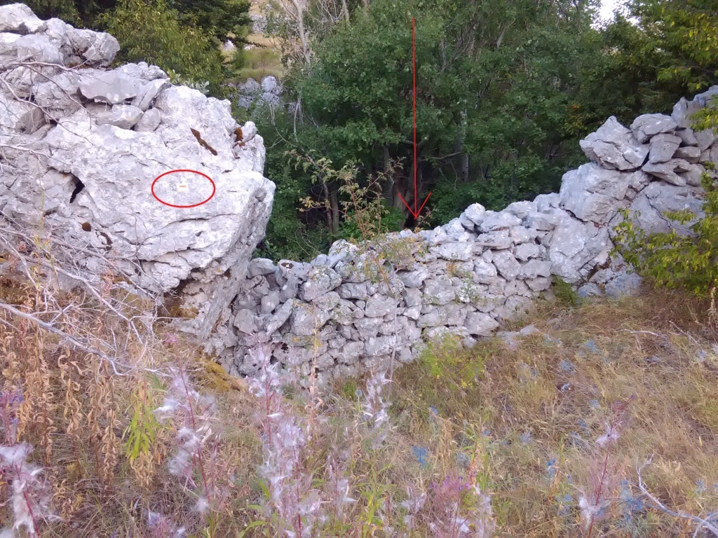 kódtábla a kőkerítés mellett